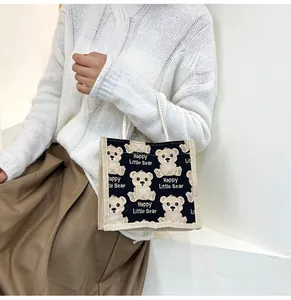 Lifestyle shot of a black linen tote bag with cartoon bears and Happy Little Bear text
