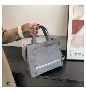 Detail of grey corduroy tote bag with reflective strip on a wooden surface