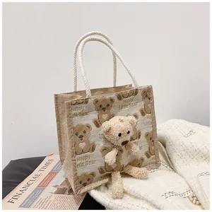Detail of canvas lunch bag featuring 3D plush bear and woven rope handles