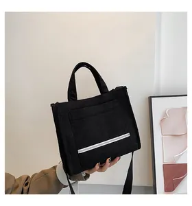 Close-up of black corduroy tote bag featuring a textured surface and front storage pocket