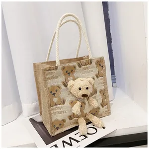 Detail of canvas tote bag with woven rope handles and cute plush bear accessory