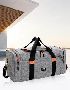 Detail of grey travel bag with orange leather accents and black durable handles