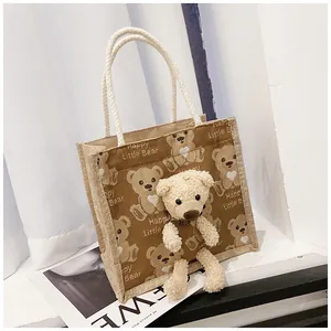 Detail of jute tote bag featuring cute plush bear decor and Happy Little Bear print