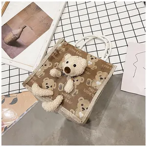 Close-up of canvas lunch bag featuring 3D plush bear and woven rope handles