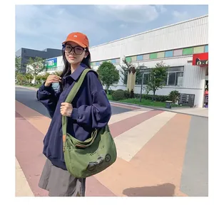 Outdoor shot of army green canvas crossbody bag with vintage motorcycle print and wide strap