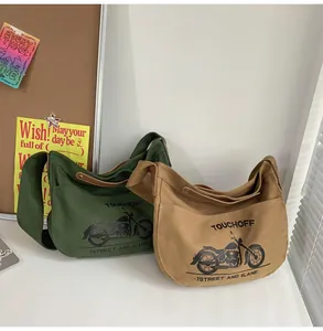 Detail of army green and khaki canvas crossbody bags featuring motorcycle graphic and wide straps