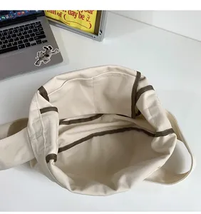 Detail view showing the spacious interior and brown trim of the beige canvas tote bag
