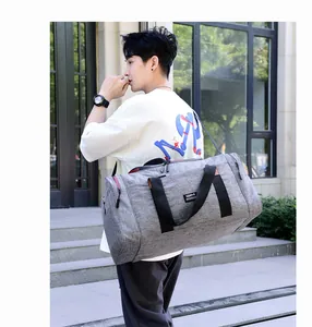 Large grey nylon travel bag with shoulder strap shown in an outdoor lifestyle setting
