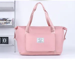 Detail view of pink travel bag showing fabric texture, brand logo and front zip pocket