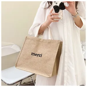 Détail d'un sac cabas en lin avec lettrage merci noir et texture en toile naturelle