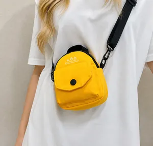 Close-up of bright yellow mini canvas bag featuring black adjustable wide strap