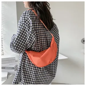Vista trasera de modelo con un bolso bandolera de media luna en nailon color naranja