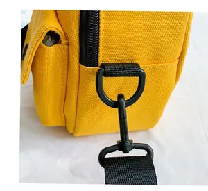 Detail of yellow canvas crossbody bag featuring D-ring buckle and side pocket stitching