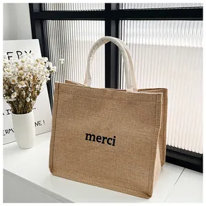 Détail de la texture d'un sac en toile de jute naturelle avec impression merci noire