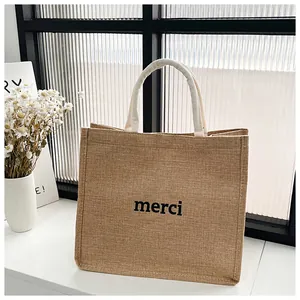 Détail du sac cabas en jute avec imprimé merci et poignées en coton blanc dans un décor chic