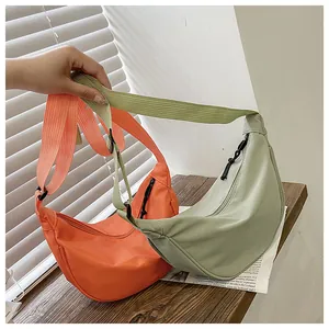 Detalle de bolsos media luna de nailon naranja y verde con correas ajustables y cremalleras