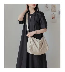 Grand sac bandoulière beige plissé porté par un mannequin, style décontracté et chic
