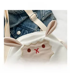 Gros plan sur la broderie de mouton et les oreilles 3D d'un sac de téléphone blanc