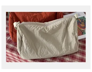 Détail de sacs bandoulière plissés minimalistes en beige et orange avec fermetures éclair
