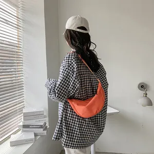 Bolso bandolera de nailon naranja vibrante combinado con una camisa a cuadros minimalista