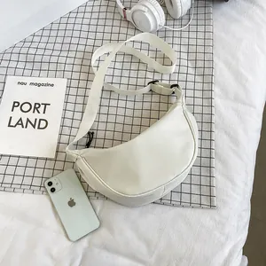 Bolso bandolera blanco minimalista en forma de medialuna con correa ajustable sobre plano