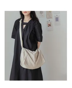 Vue détaillée du grand sac bandoulière plissé en toile crème avec une sangle réglable
