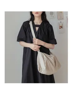 Vue détaillée du grand sac bandoulière en toile blanc cassé avec large sangle sur modèle