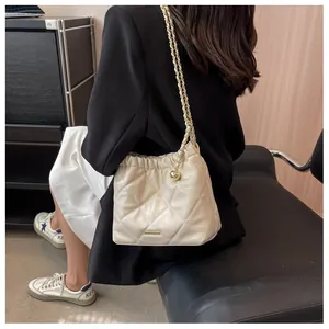 Close-up of beige quilted bucket bag with gold chain strap and drawstring detail