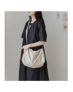 Détail du sac hobo en toile beige montrant la texture plissée et le drapé souple