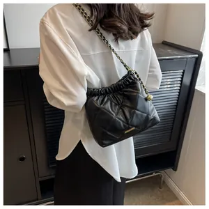 Detail of black quilted bucket bag with gold chain strap and drawstring closure