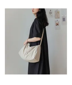 Détail du sac bandoulière en toile beige clair montrant sa texture et son beau drapé