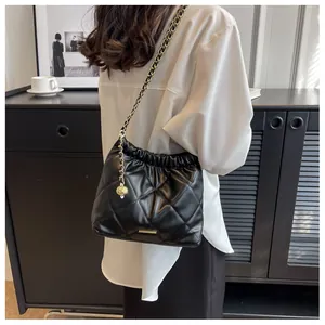 Close-up of quilted black leather shoulder bag with golden chain and sphere pendant