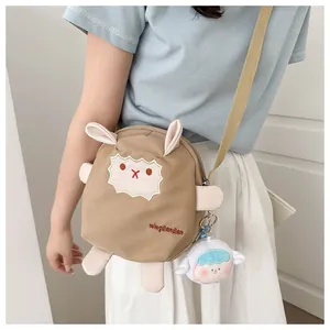 Détail du sac bandoulière mouton marron avec pendentif en peluche et sangle tissée