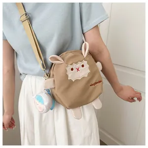 Détail d'un sac bandoulière mouton marron avec broderie et pendentif en peluche