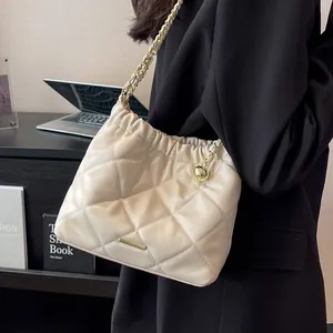 Chic beige quilted bucket bag with gold chain strap and spherical charm detail