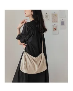 Détail d'un sac bandoulière plissé en toile crème avec bandoulière réglable spacieuse