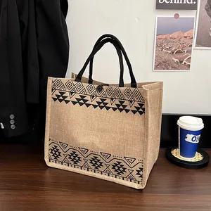 Large burlap tote bag with black tribal geometric patterns and rope handles on a wood table