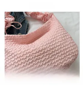 Détail du tissu gaufré rose et de la bandoulière froncée sur le sac fourre-tout