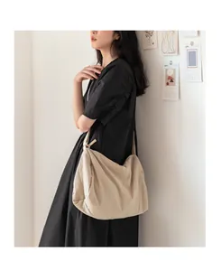 Gros plan d'un sac bandoulière beige en toile plissée avec large sangle d'épaule