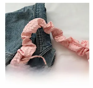 Détail de la bandoulière rose à texture gaufrée et design à volants pour sac à main