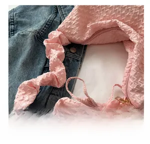Gros plan sur le sac plissé rose en tissu gaufré avec une bandoulière assortie élégante