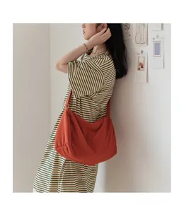 Gros plan d'un grand sac à bandoulière plissé en toile orange brûlé sur un mannequin