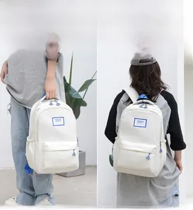 Detail of cream white minimalist backpack showing spacious compartments and blue zip pullers