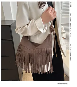 Detail showing long suede fringe and braided strap knots on a brown crossbody bag