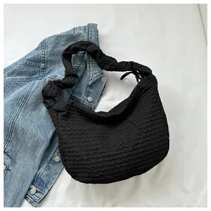 Détail du sac croissant plissé noir avec texture ondulée douce sur fond blanc épuré