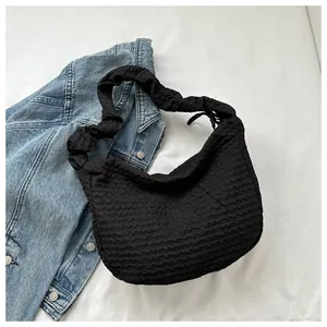Gros plan d'un sac hobo noir avec texture plissée et bandoulière style chouchou