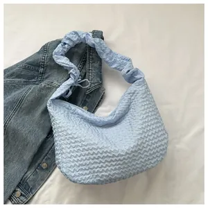 Détail du sac à bandoulière bleu clair à texture popcorn et bandoulière plissée