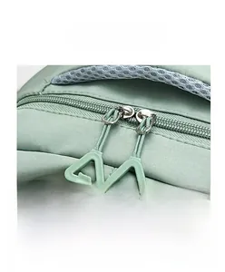 Detail of dual zipper closure and mesh handle on green nylon backpack for students