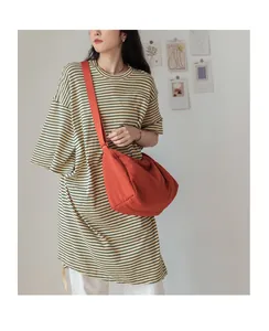 Détail d'un sac bandoulière en toile orange vif porté avec un t-shirt rayé décontracté