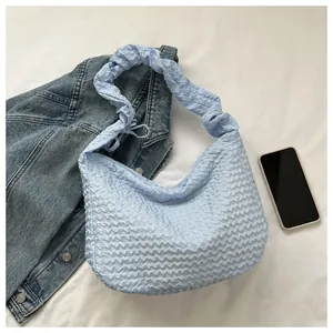 Détail du sac croissant bleu clair avec texture à bulles unique sur surface blanche